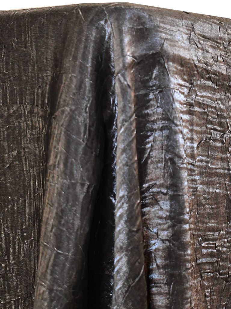 Dark, textured fabric draped over an unseen form, with crinkled surface and reflective highlights.
