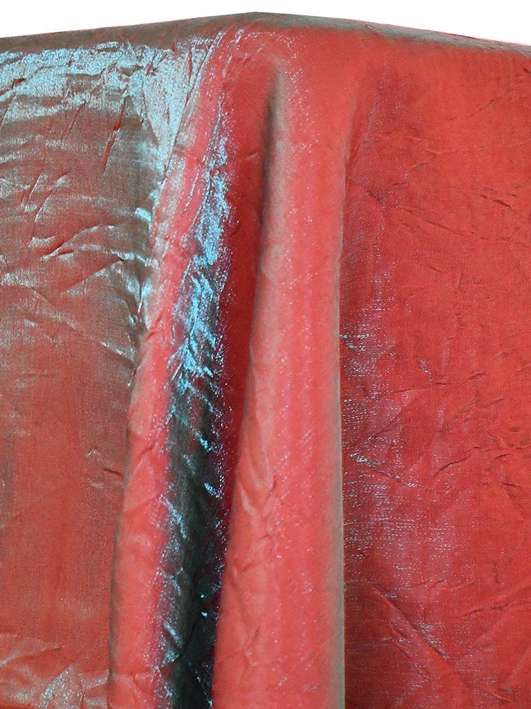 Red fabric, folded and textured, with a dark crease running vertically.