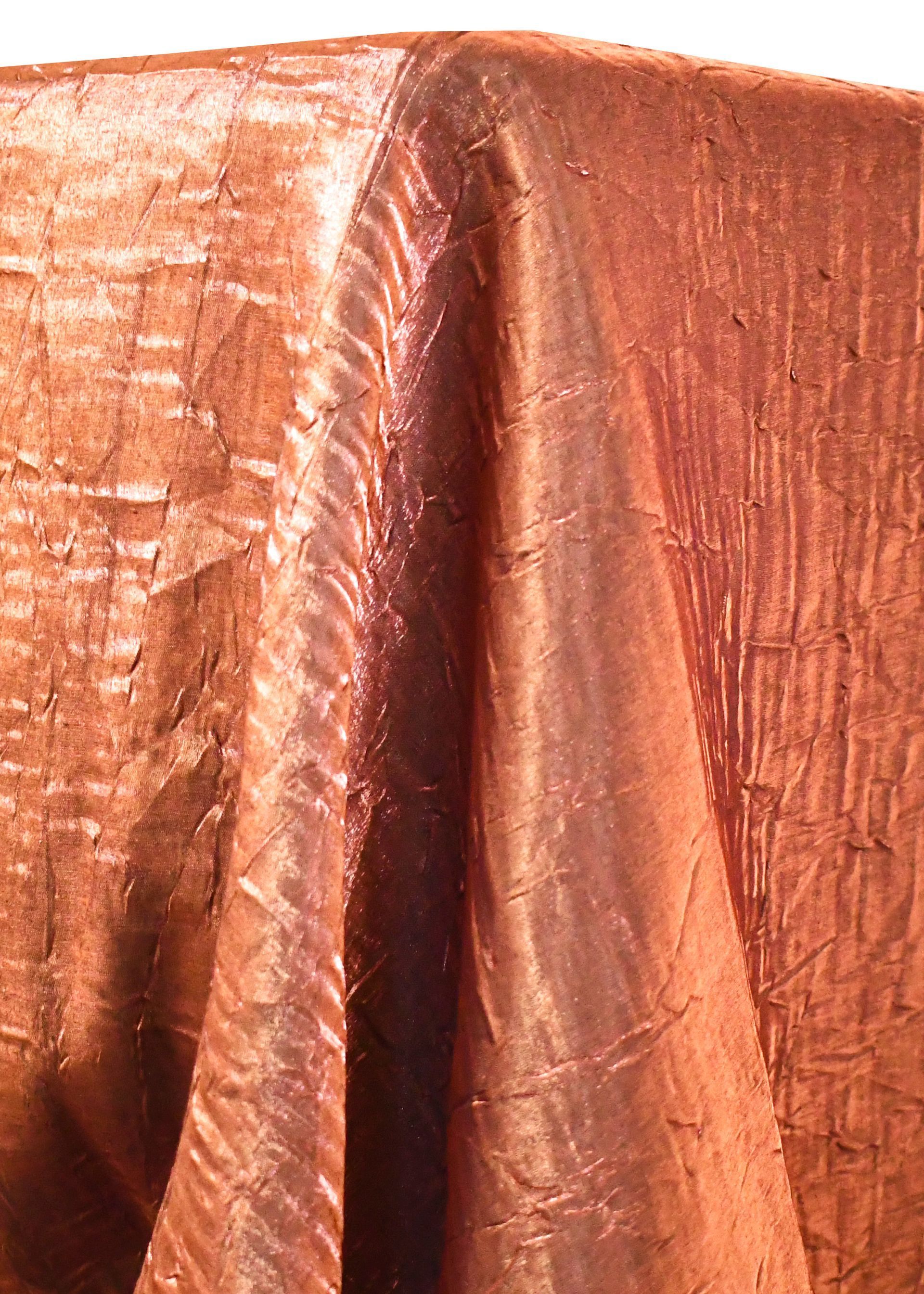 Copper-colored textured tablecloth draped over a surface, with folds and highlights.
