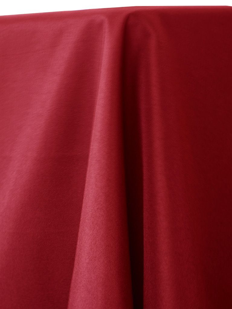 Close-up of a draped, red satin fabric with highlights and shadows.