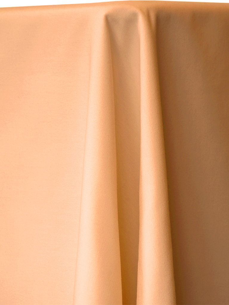 Peach-colored fabric draped over a surface, with soft folds and shadows.