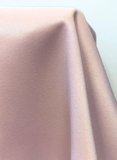 Close-up of pink fabric with a subtle sheen, draped with soft folds.