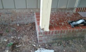 Front porch with brick steps, white column, and a black power tool on the red-tiled landing