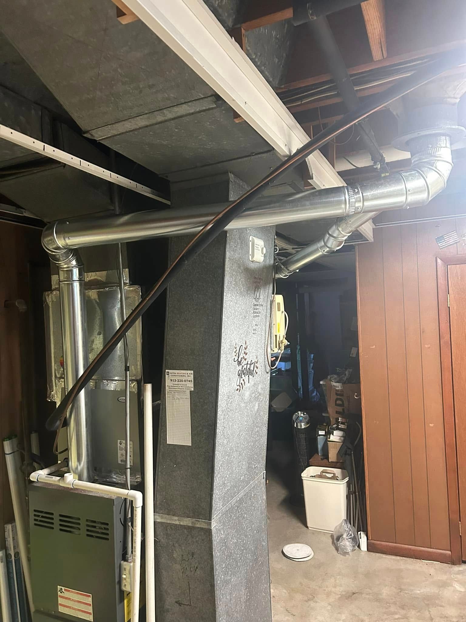 HVAC system in a basement: furnace, ductwork, insulated column, and electrical conduit.