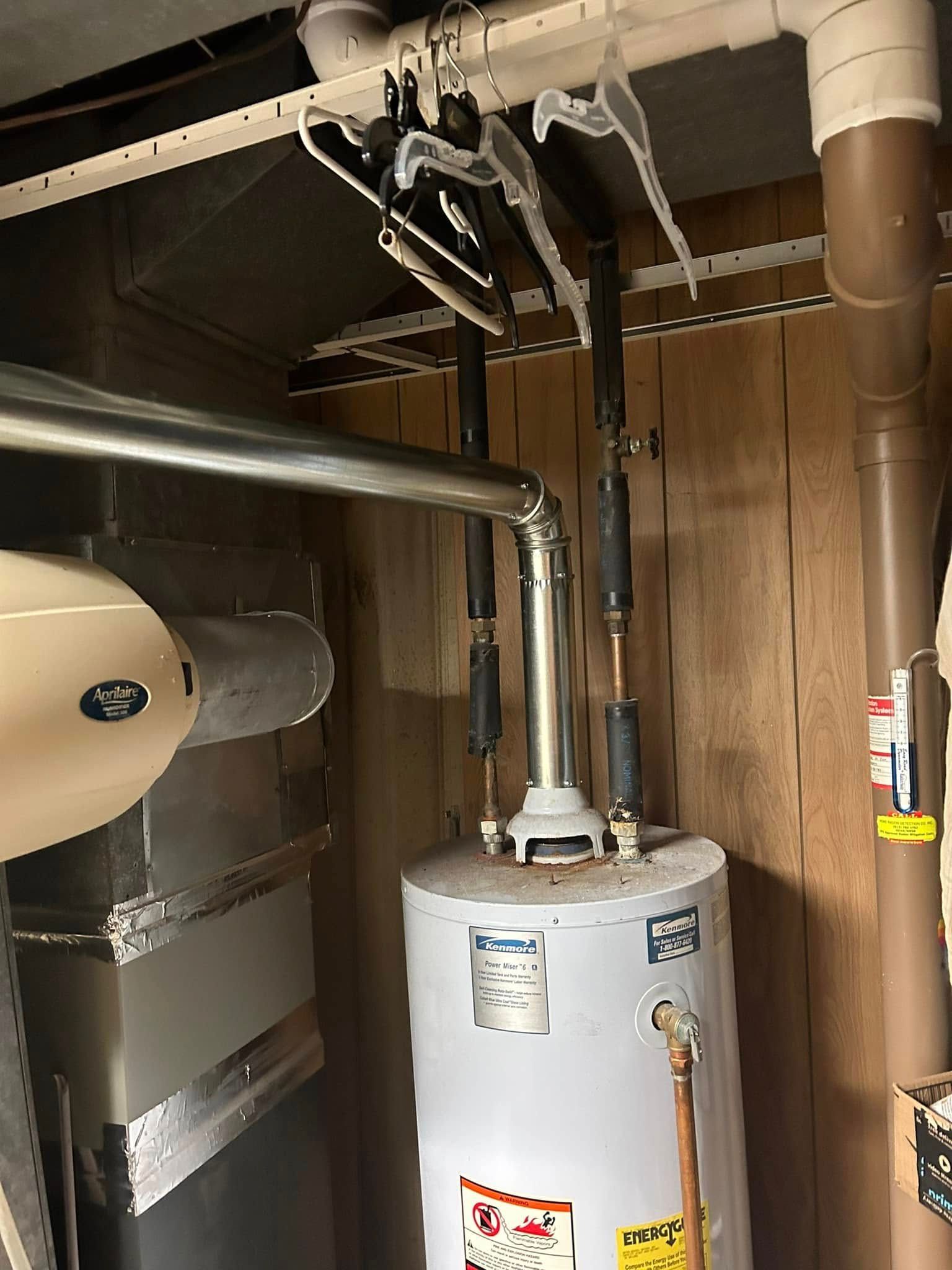 Water heater and vent pipe in utility room; hangers on vent.