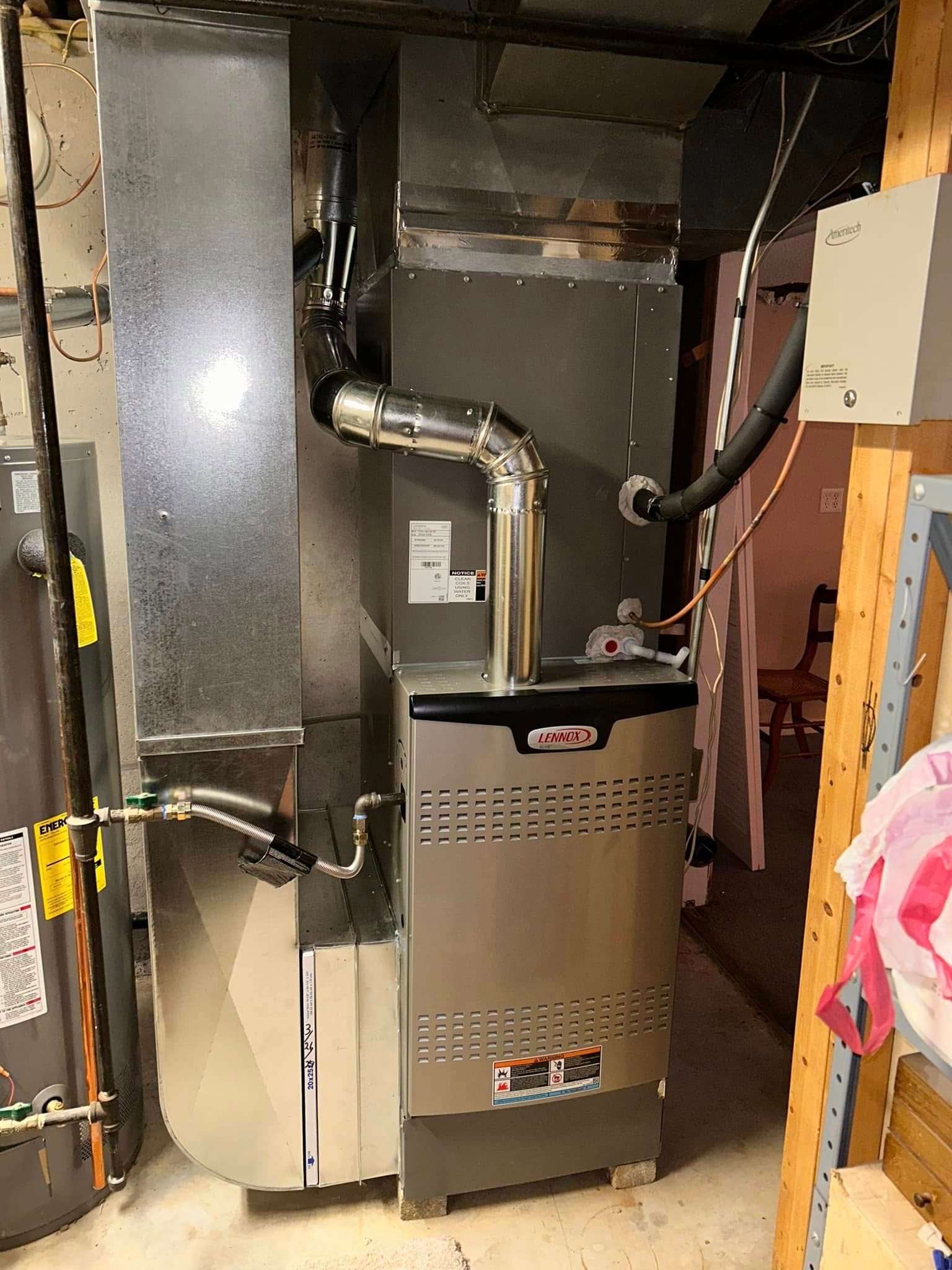 Furnace and related ductwork in a basement. Metal components, silver/gray color. Electrical wires visible.