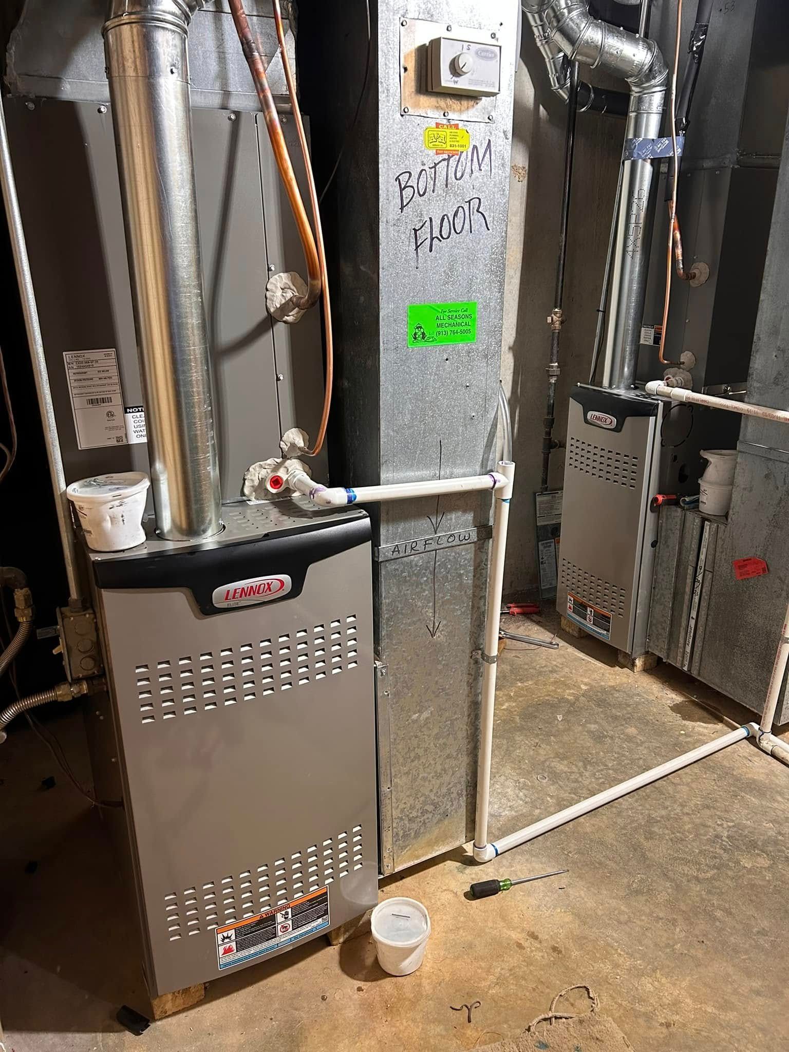 A Lennox furnace in a basement. Gray metal with white PVC pipes and ductwork.
