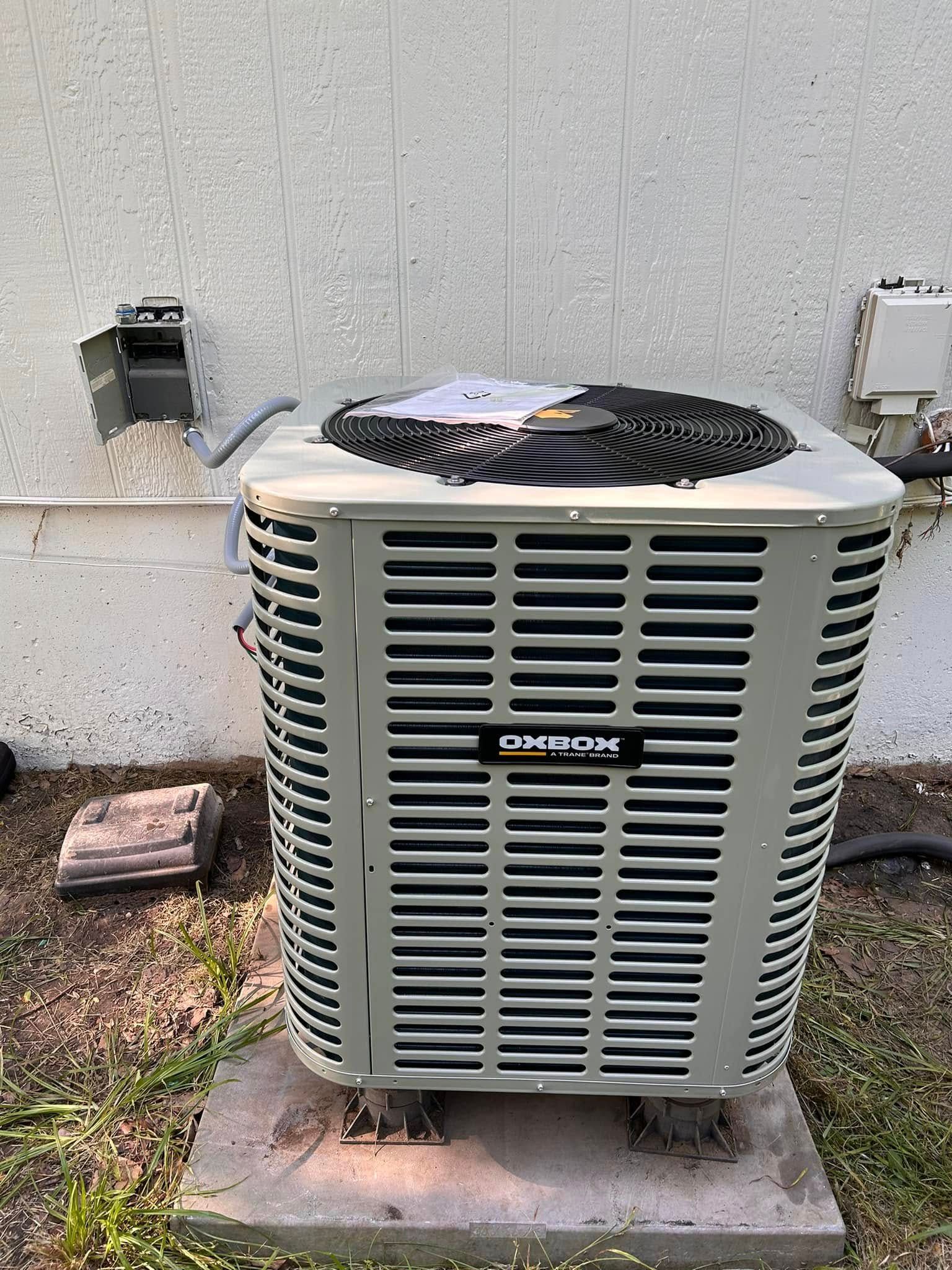 Air conditioning unit outside against a stucco wall.