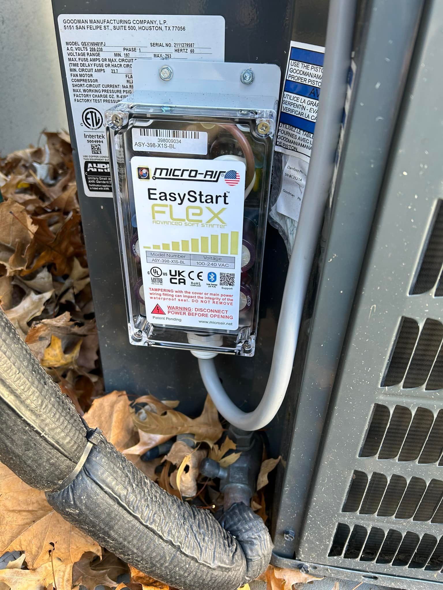An EasyStart Flex device installed on an AC unit. It’s in a clear plastic case with a gray conduit attached.