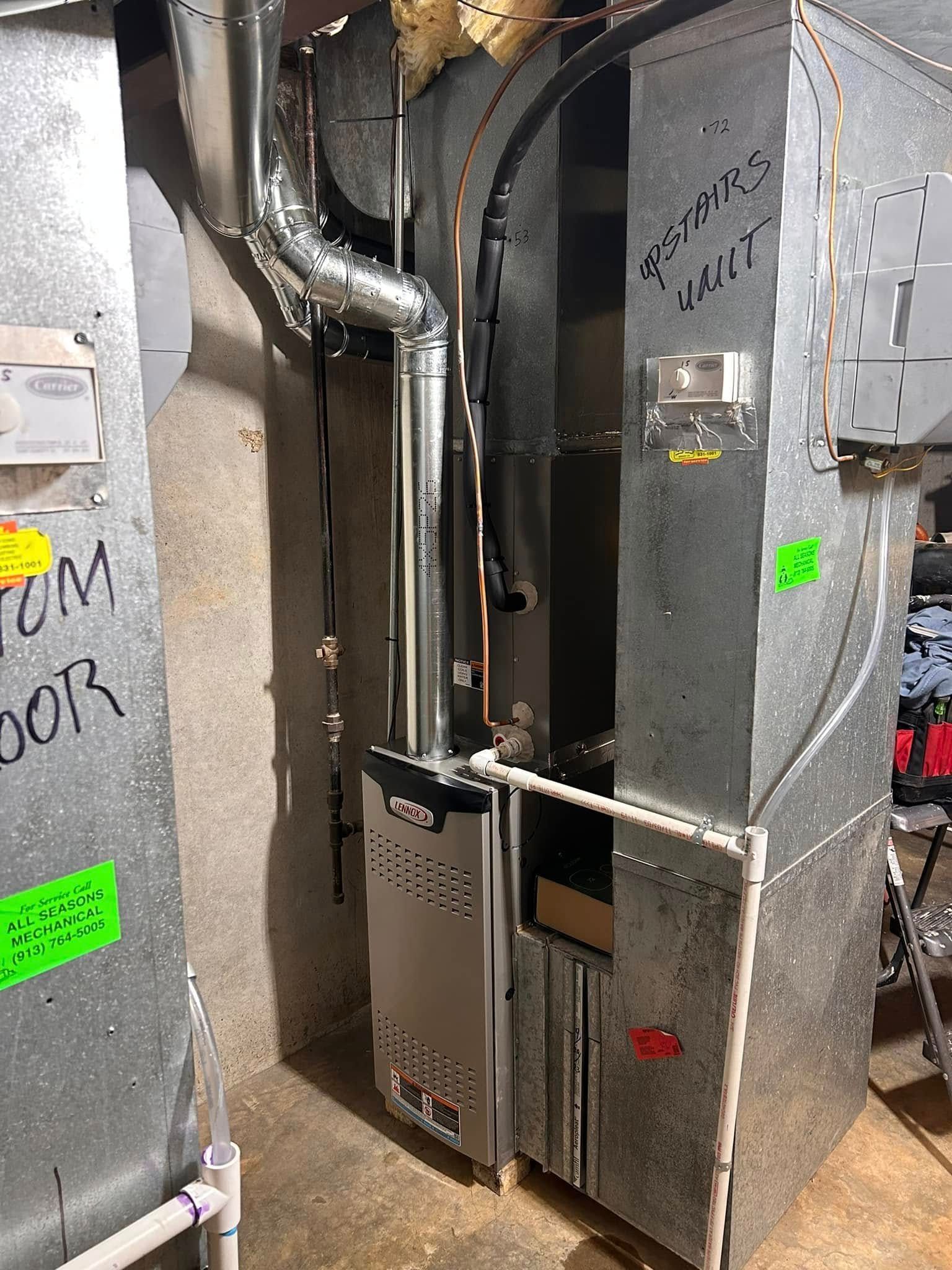 Furnace unit with metal ductwork in a basement. Silver and gray tones dominate.