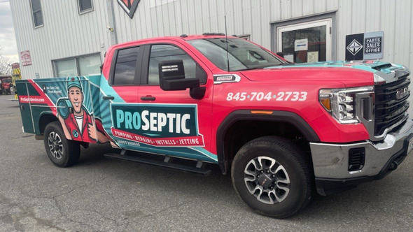 Red and teal ProSeptic truck parked in front of a building; phone number on the side.