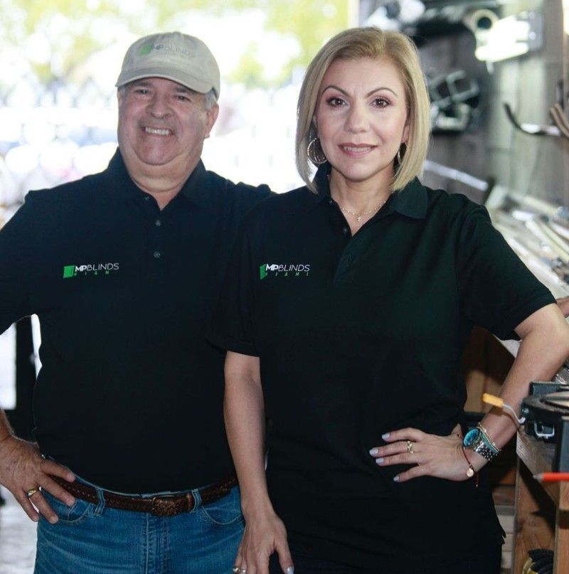 Two people wearing matching black shirts, smiling, posing indoors.