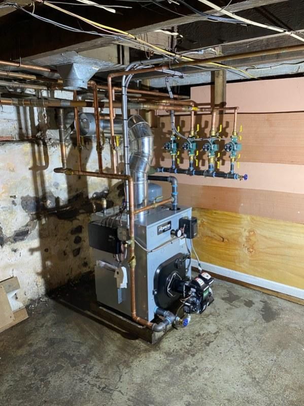 A furnace with copper pipes in a basement.