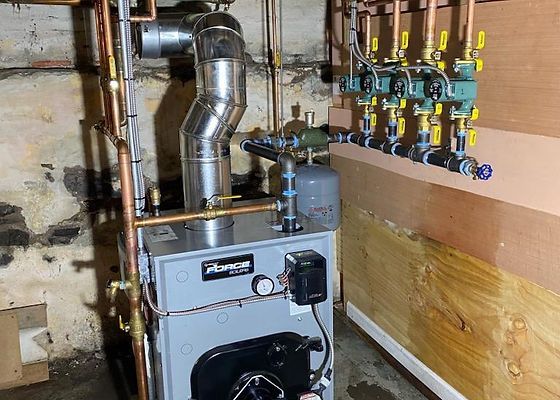 A Force boiler with connected pipes and valves in a basement setting.