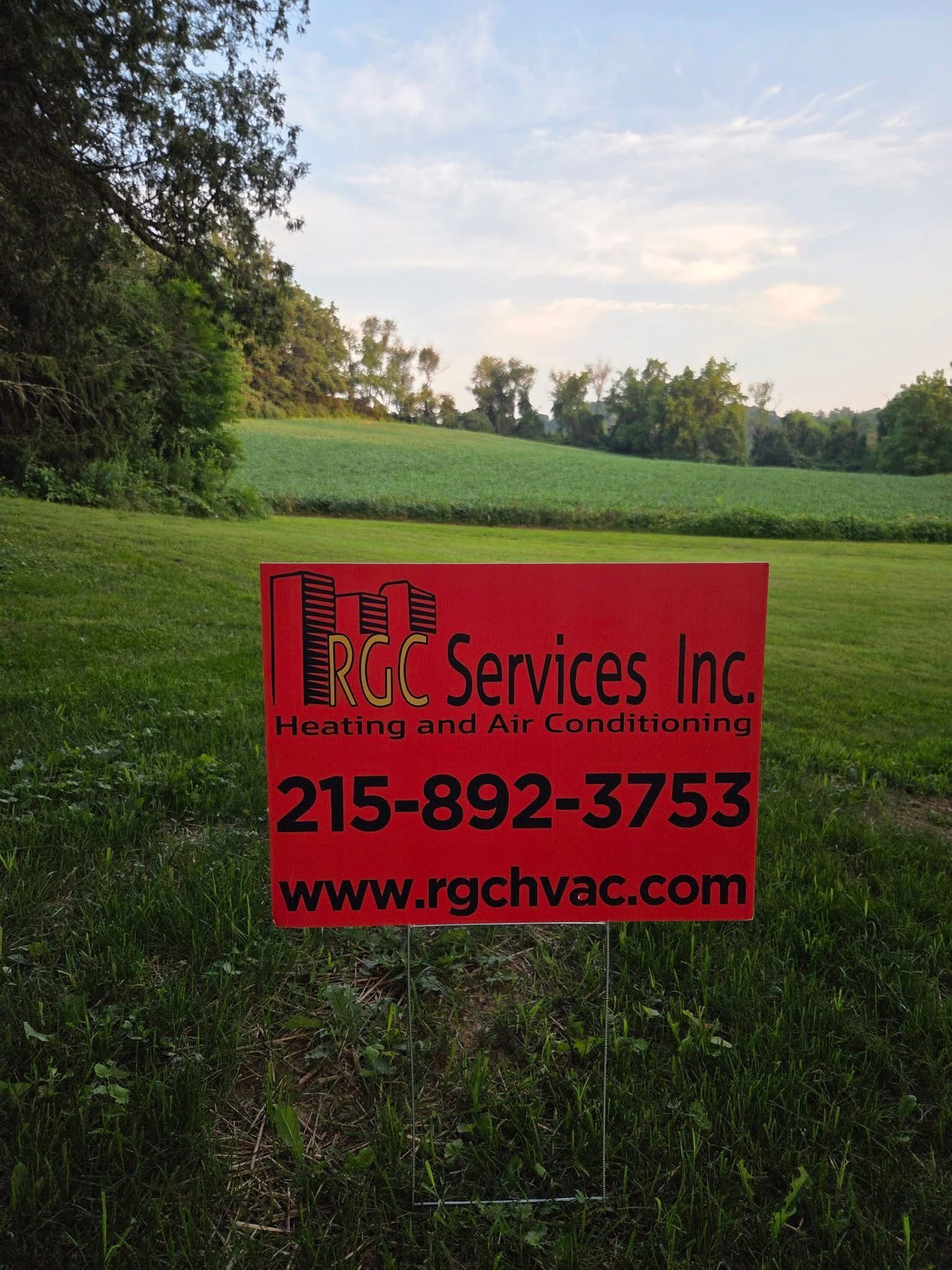 Red RGC Services sign in a grassy field, advertising heating and air conditioning, with phone number and website.