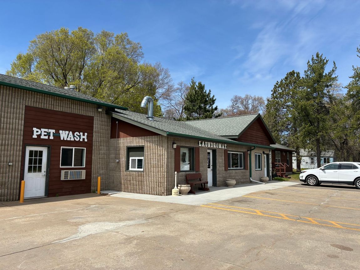 PET WASH storefront with brick building, green roof, and white car parked outside