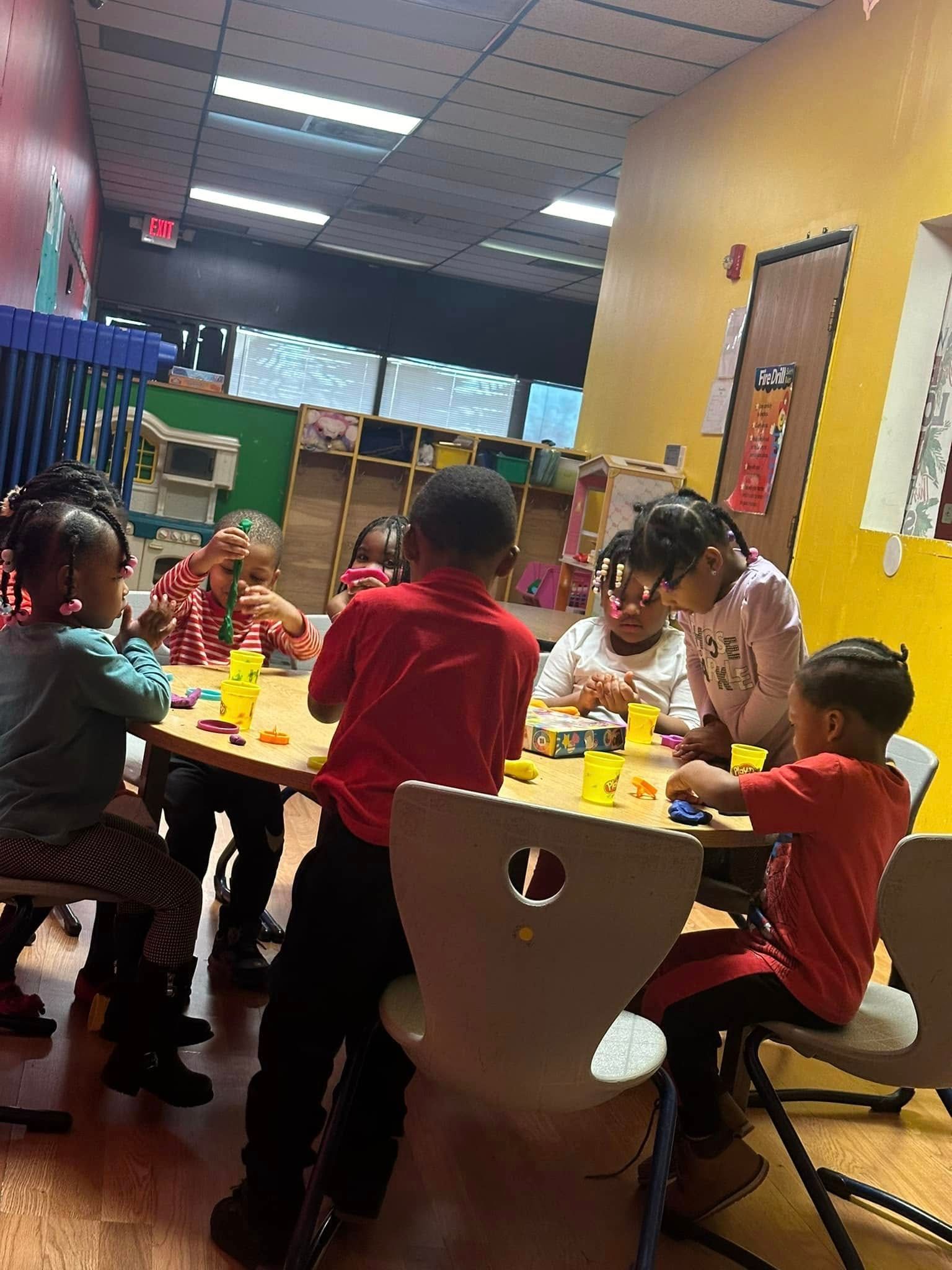Children at a table playing with colorful clay in a brightly lit classroom.