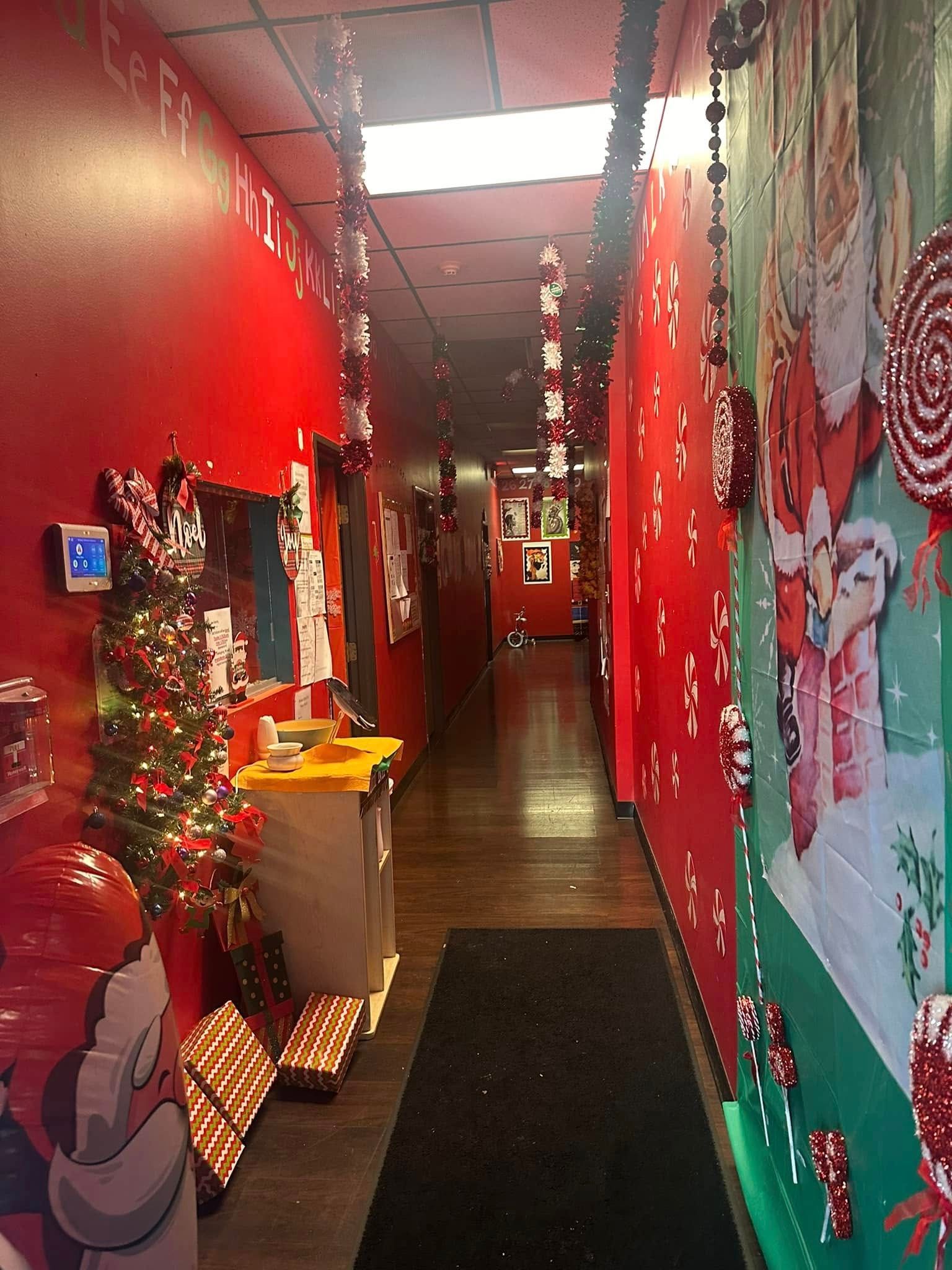 Christmas-decorated hallway with red walls, candy decorations, a Christmas tree, and Santa illustrations.