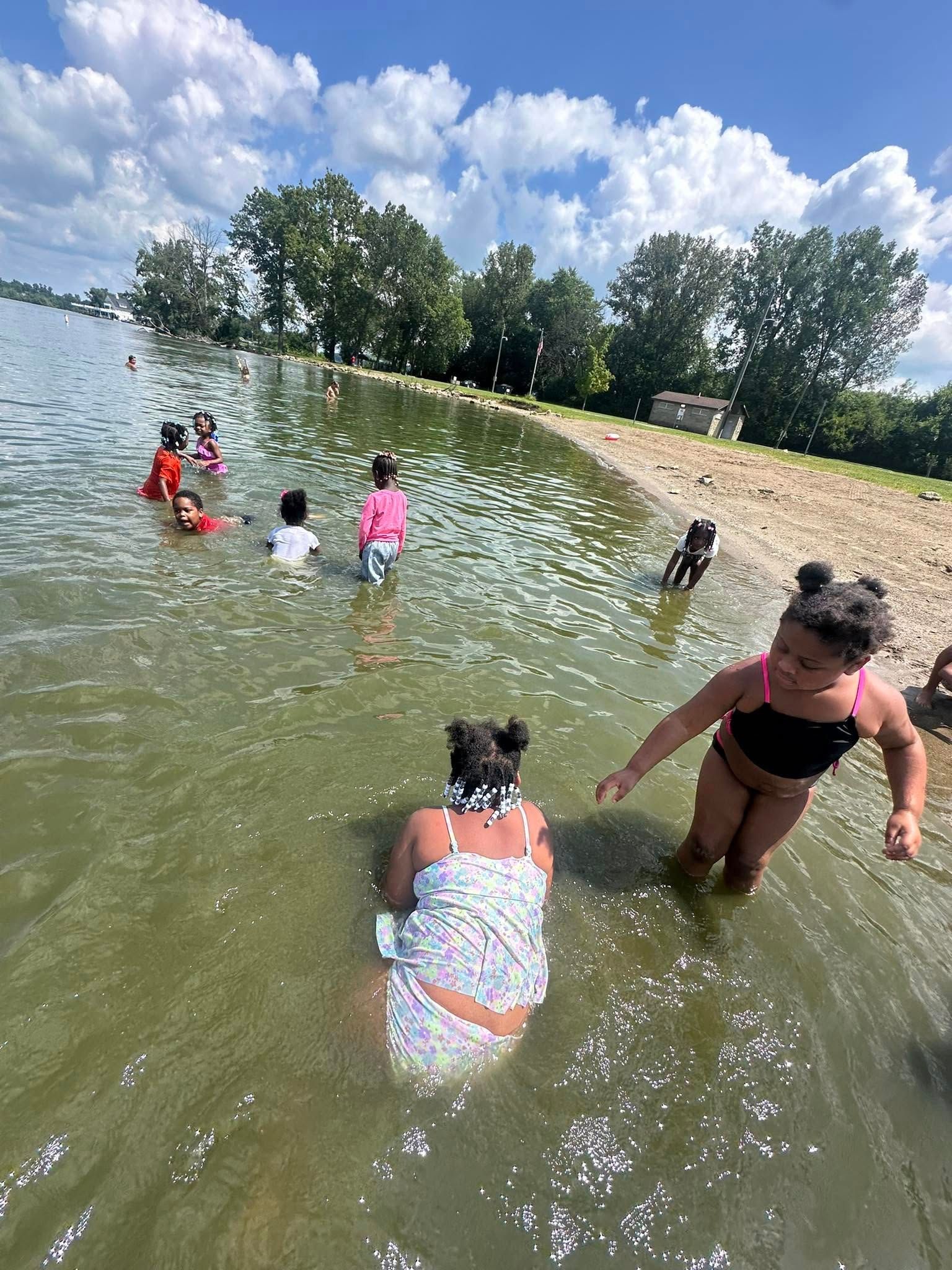 Children playing in shallow water at a beach on a sunny day.