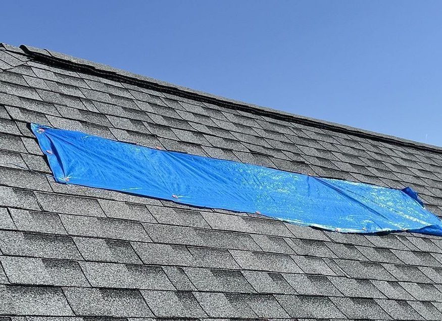 Storm damaged roof inspection with blue tarp to protect the interior in Ankeny, IA.