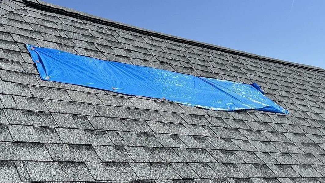 Blue tarp installed after a wind storm caused shingle to blow off the shingled roof in Ankeny, IA.