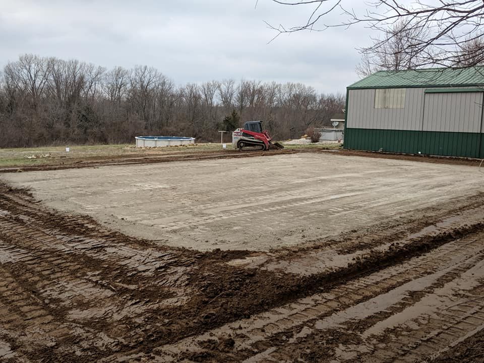 A muddy field with a green building in the background.