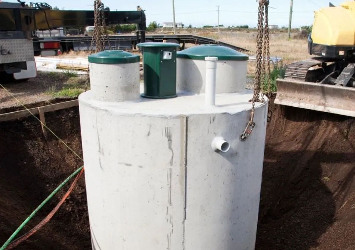 A large concrete tank is being lifted by a crane.