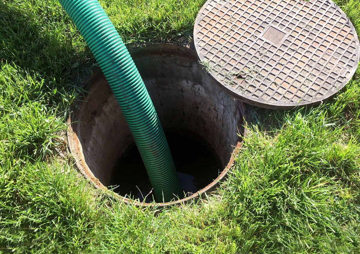 A green hose is coming out of a manhole cover.