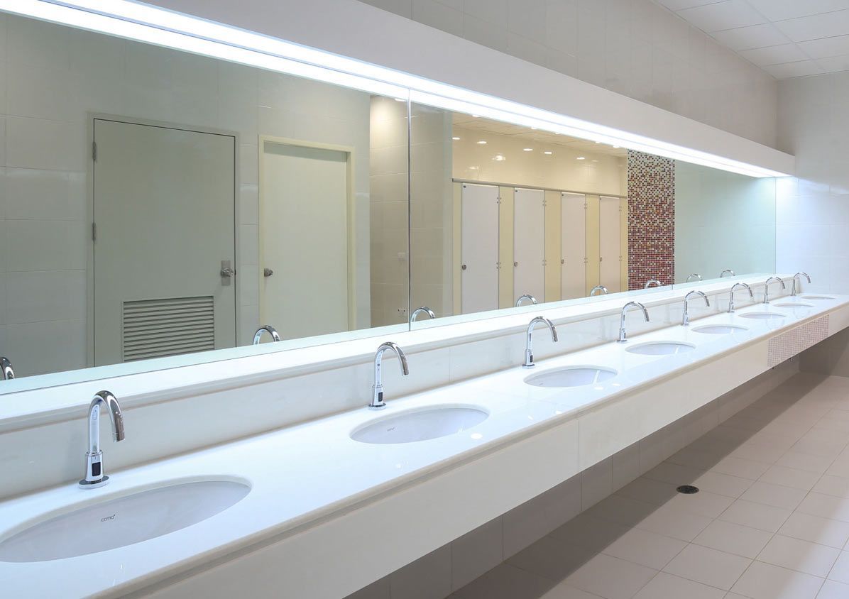 A bathroom with a long row of sinks and a large mirror.