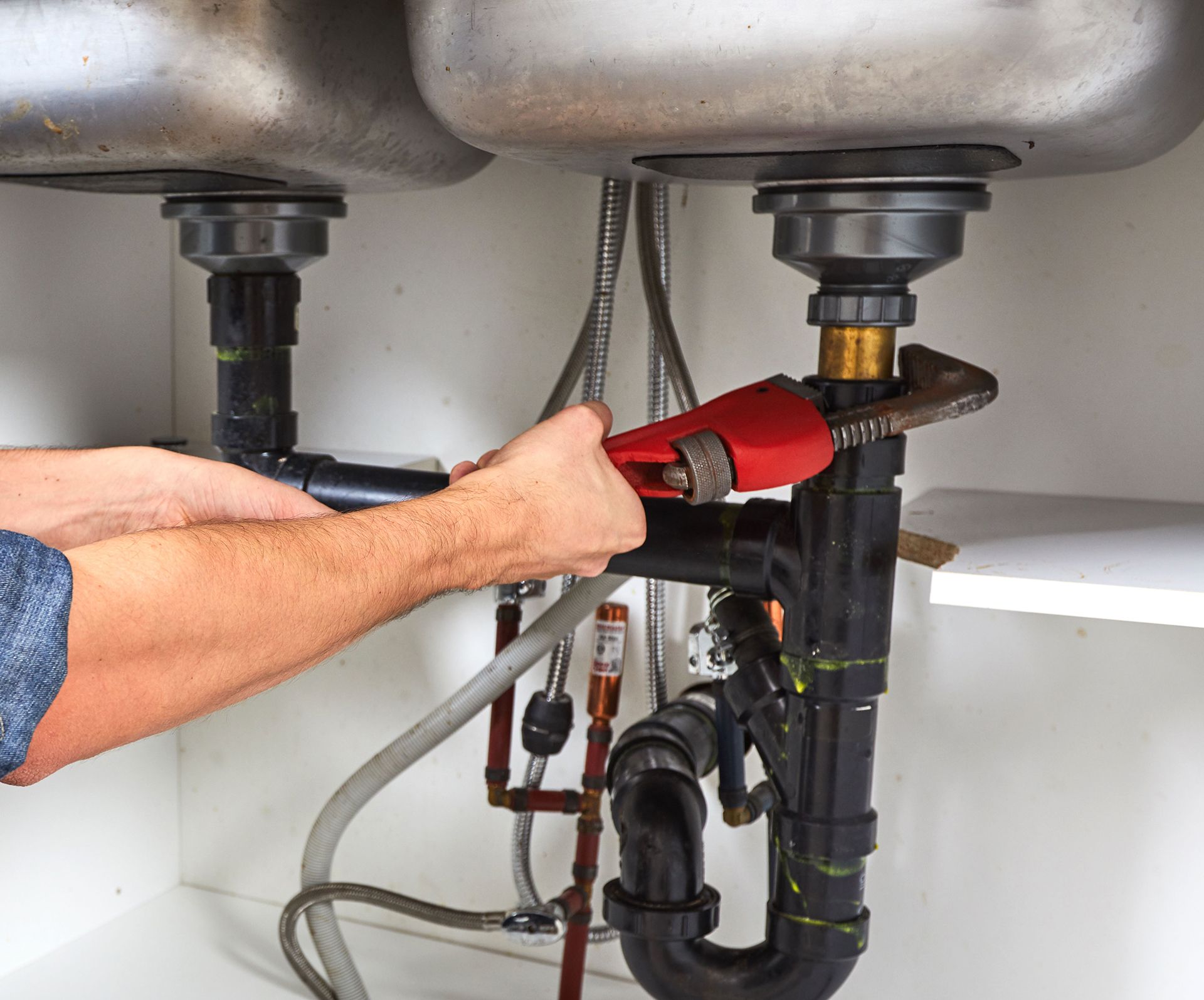 A man is fixing a sink with a wrench