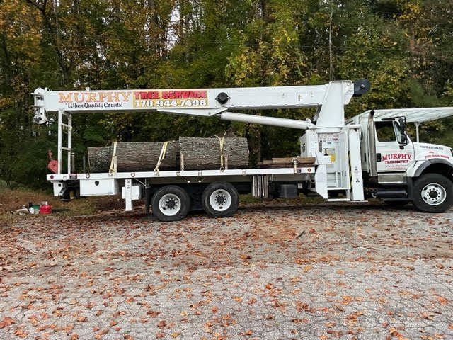 A white truck with a crane on the back is parked in a parking lot.