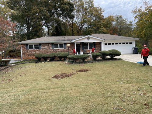 A man in a red jacket is walking in front of a house.