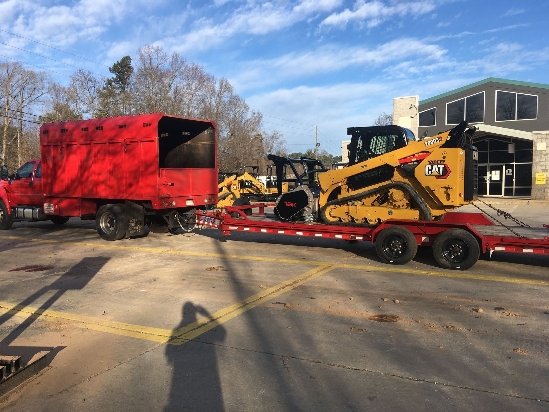 A red truck is towing a bulldozer on a trailer.