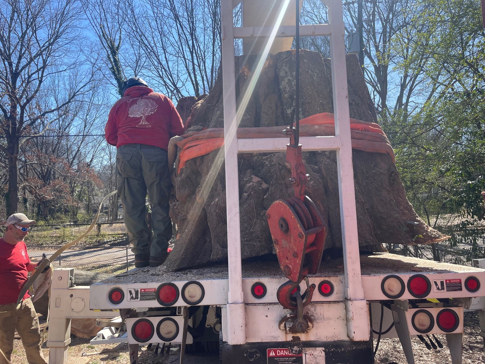A man in a red sweatshirt is standing on the back of a truck.