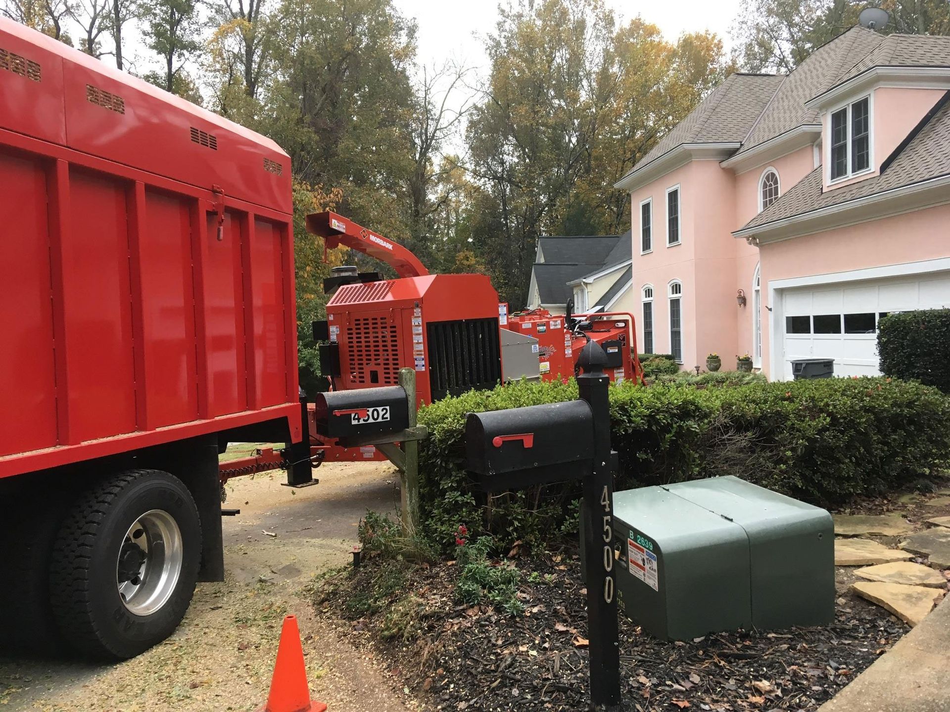 A red truck is parked in front of a house next to a mailbox.