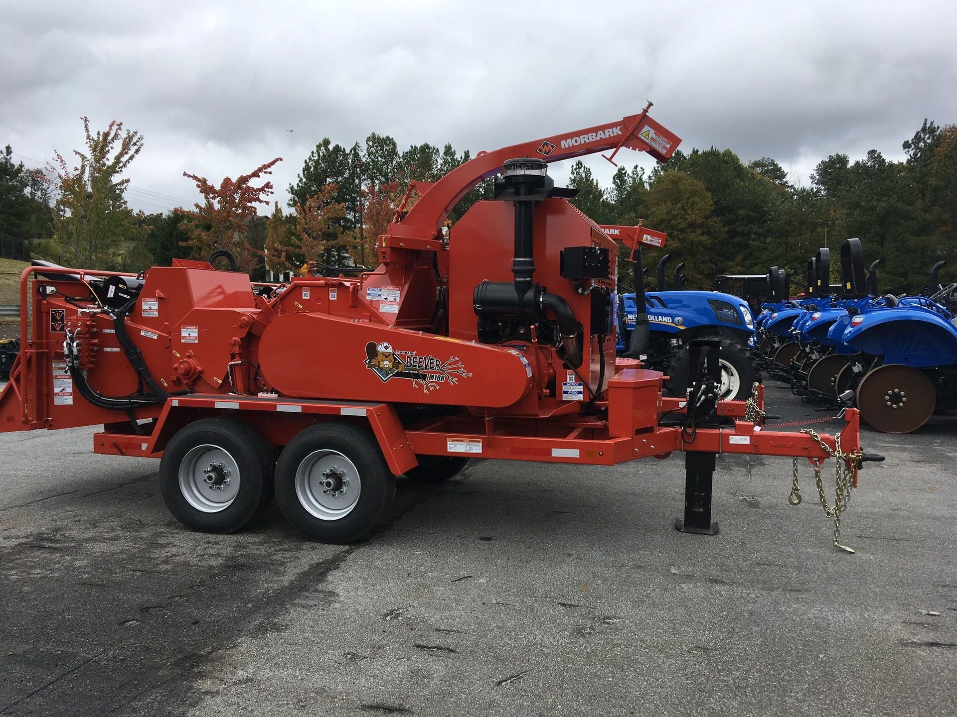 A red machine is parked on a trailer in a parking lot.