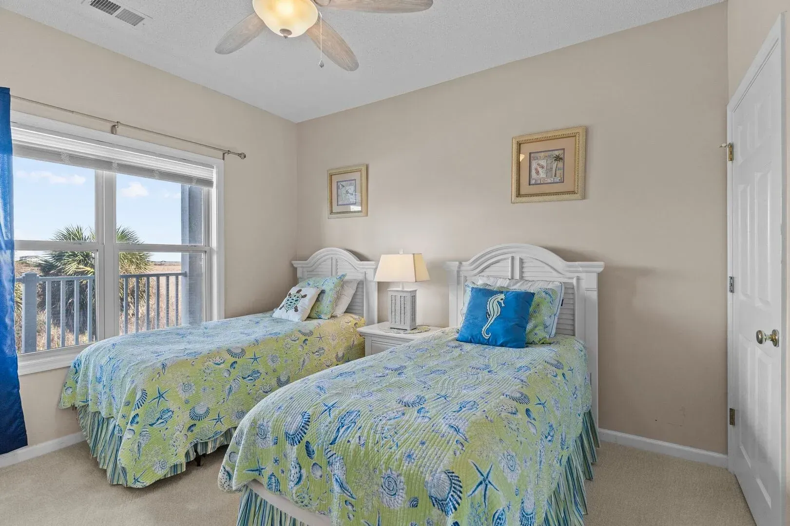Bright bedroom with two twin beds, floral bedding, a window, and a ceiling fan
