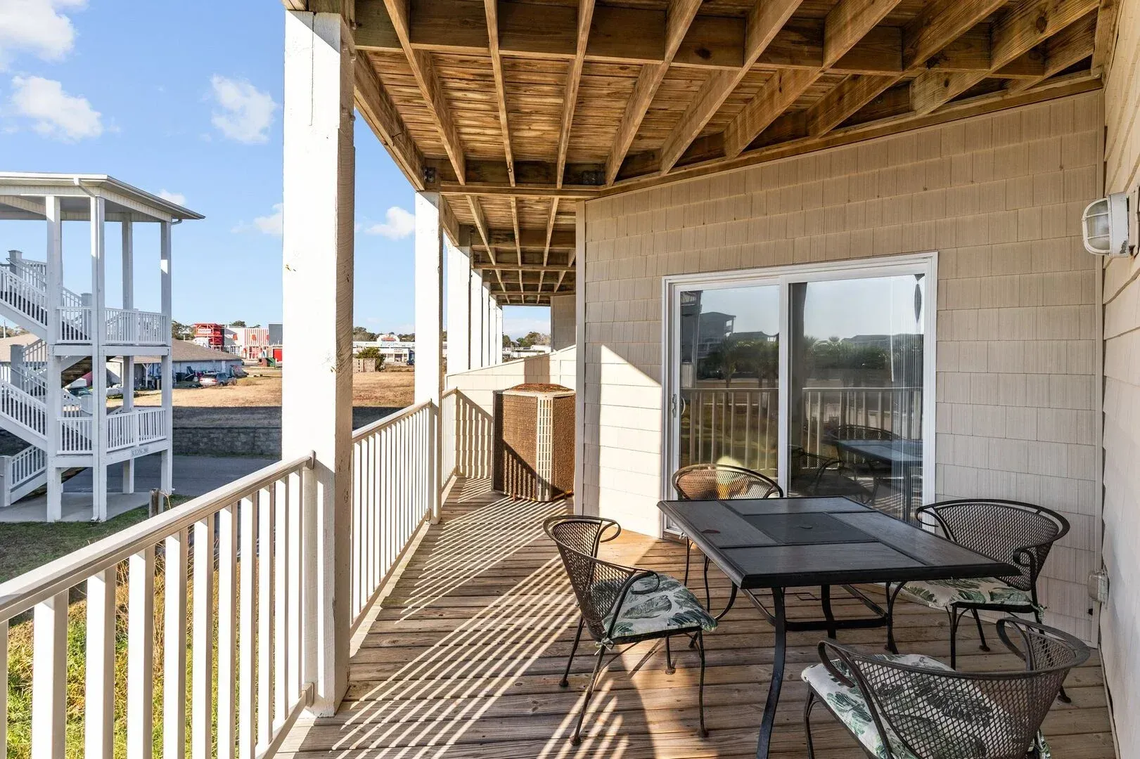 Covered balcony with outdoor dining table, chairs, and a view of neighboring houses