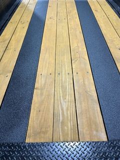 Wooden trailer bed with black strips, diamond plate bumper.