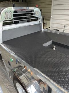 Diamond-plated truck bed with headache rack, gooseneck hitch.