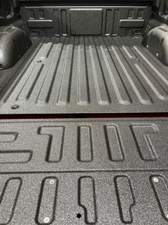 Truck bed with textured coating, ribbed floor, and embossed 