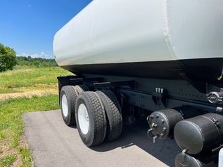 White tanker truck with black undercarriage and tires on a paved surface.