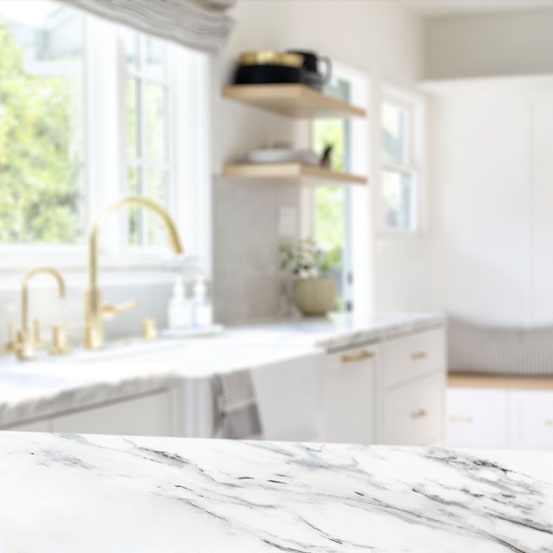 A kitchen with a marble counter top and a sink.