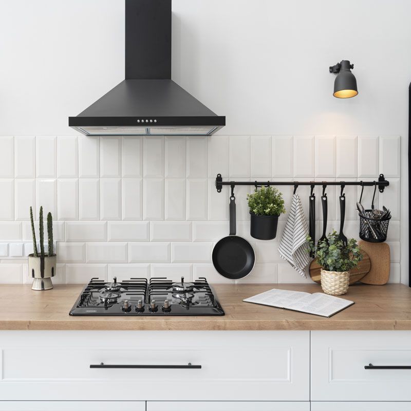 A kitchen with a stove top oven and a hood above it