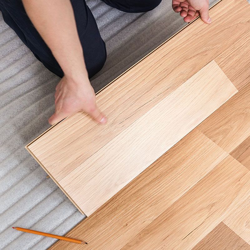 A person is laying a piece of wood on the floor.