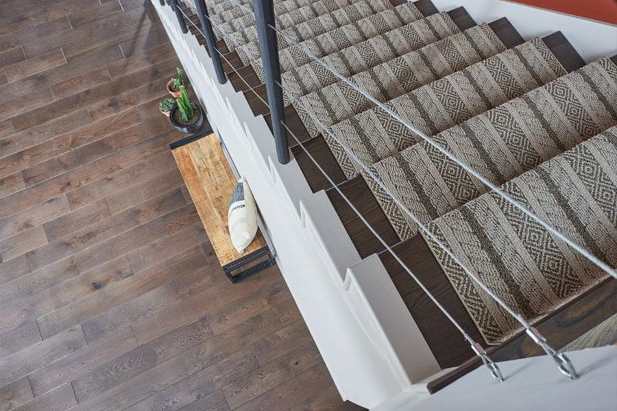 An aerial view of a staircase with a carpeted staircase and a metal railing.