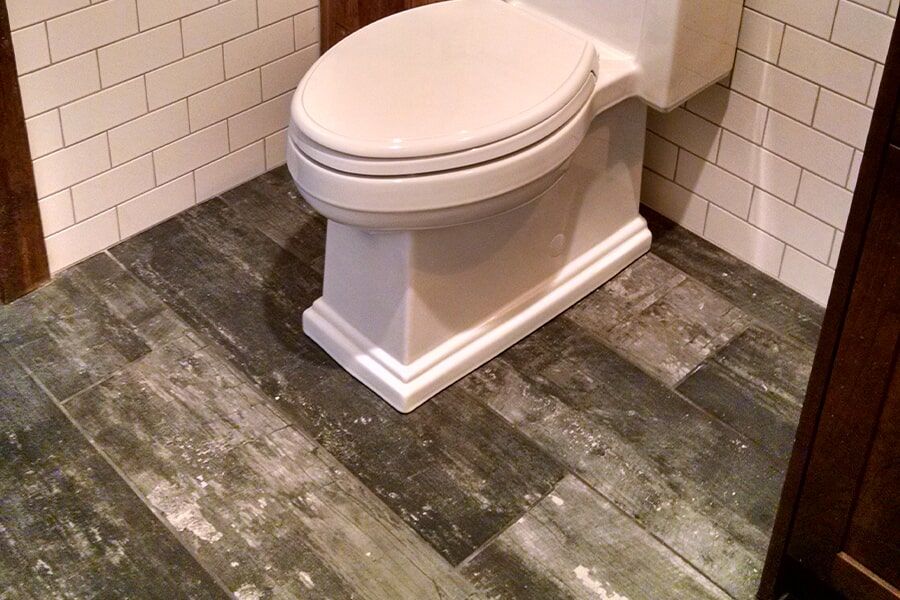 A toilet is sitting on a tiled floor in a bathroom.