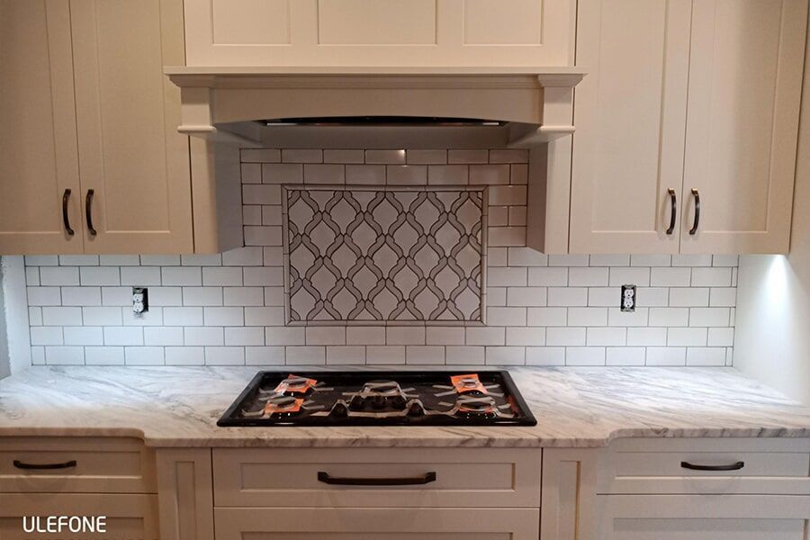 A kitchen with white cabinets and a stove top oven.