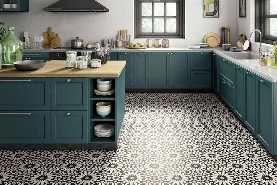 A kitchen with green cabinets and a black and white tile floor.