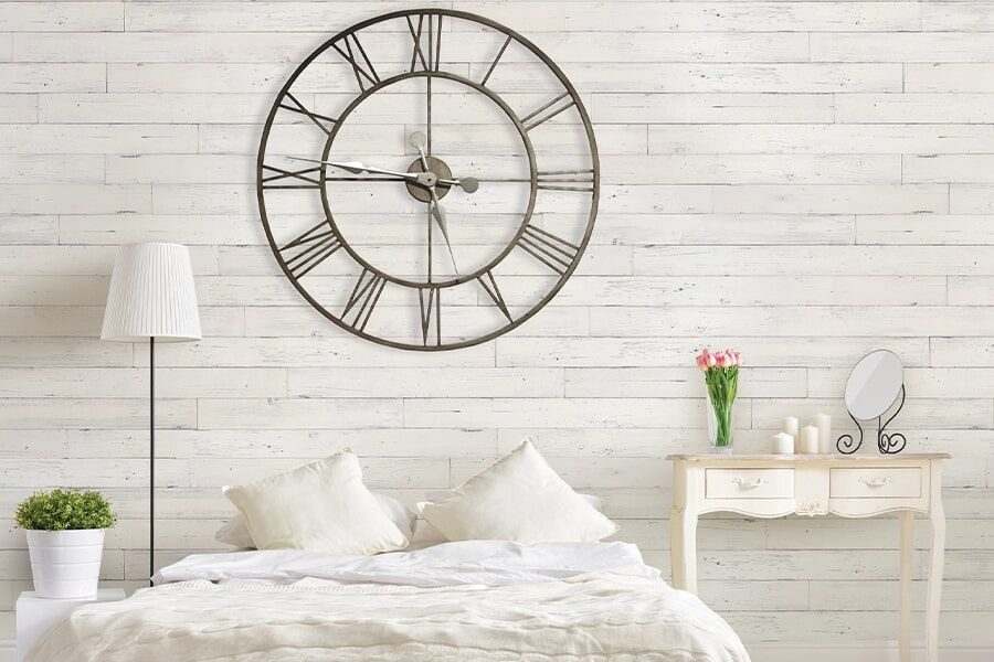 A bedroom with a large clock on the wall above the bed.